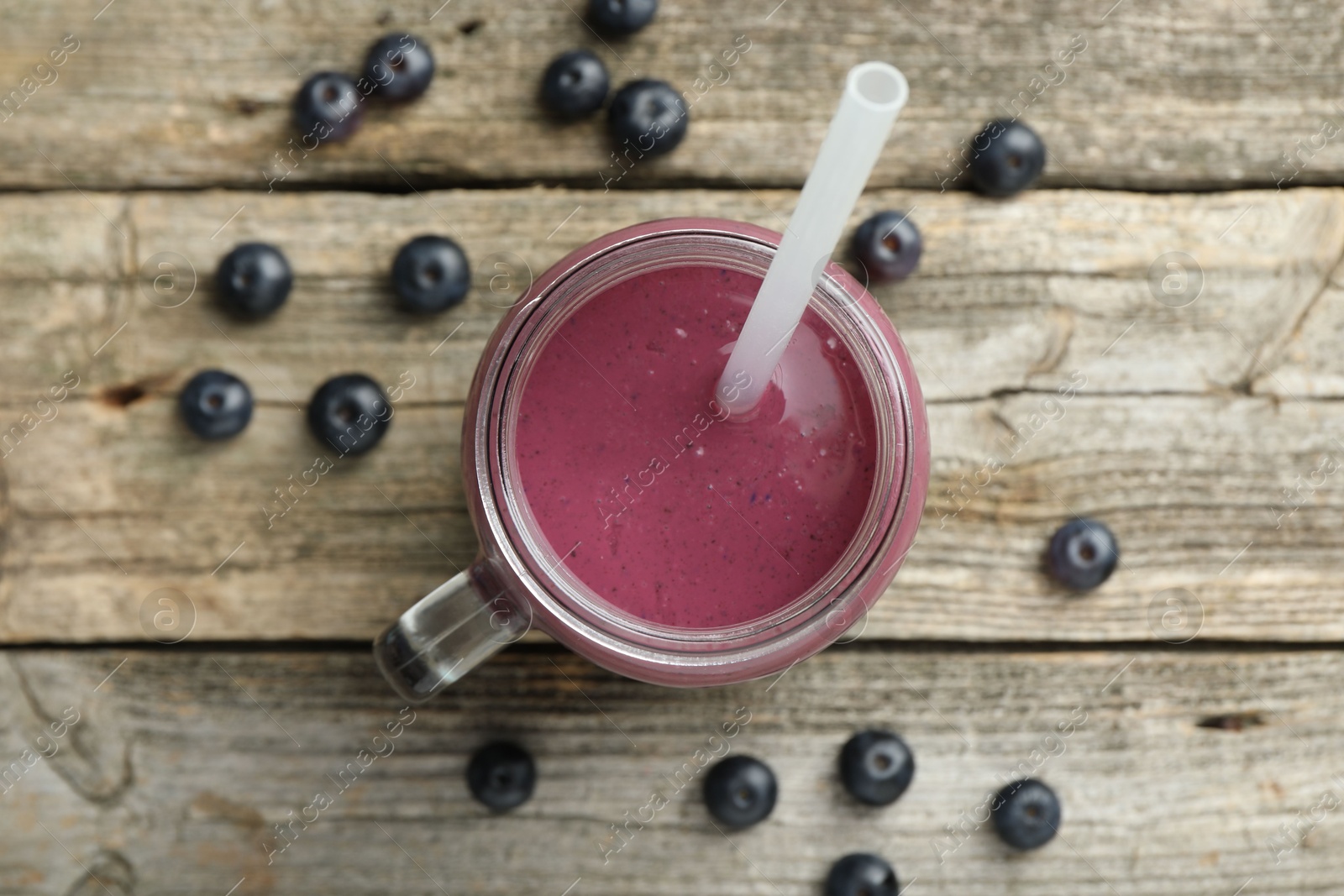 Photo of Tasty fresh acai juice in mason jar on wooden table, top view