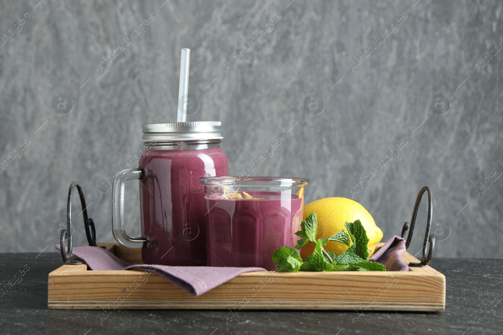 Photo of Tasty fresh acai juice with mint and lemon on grey table