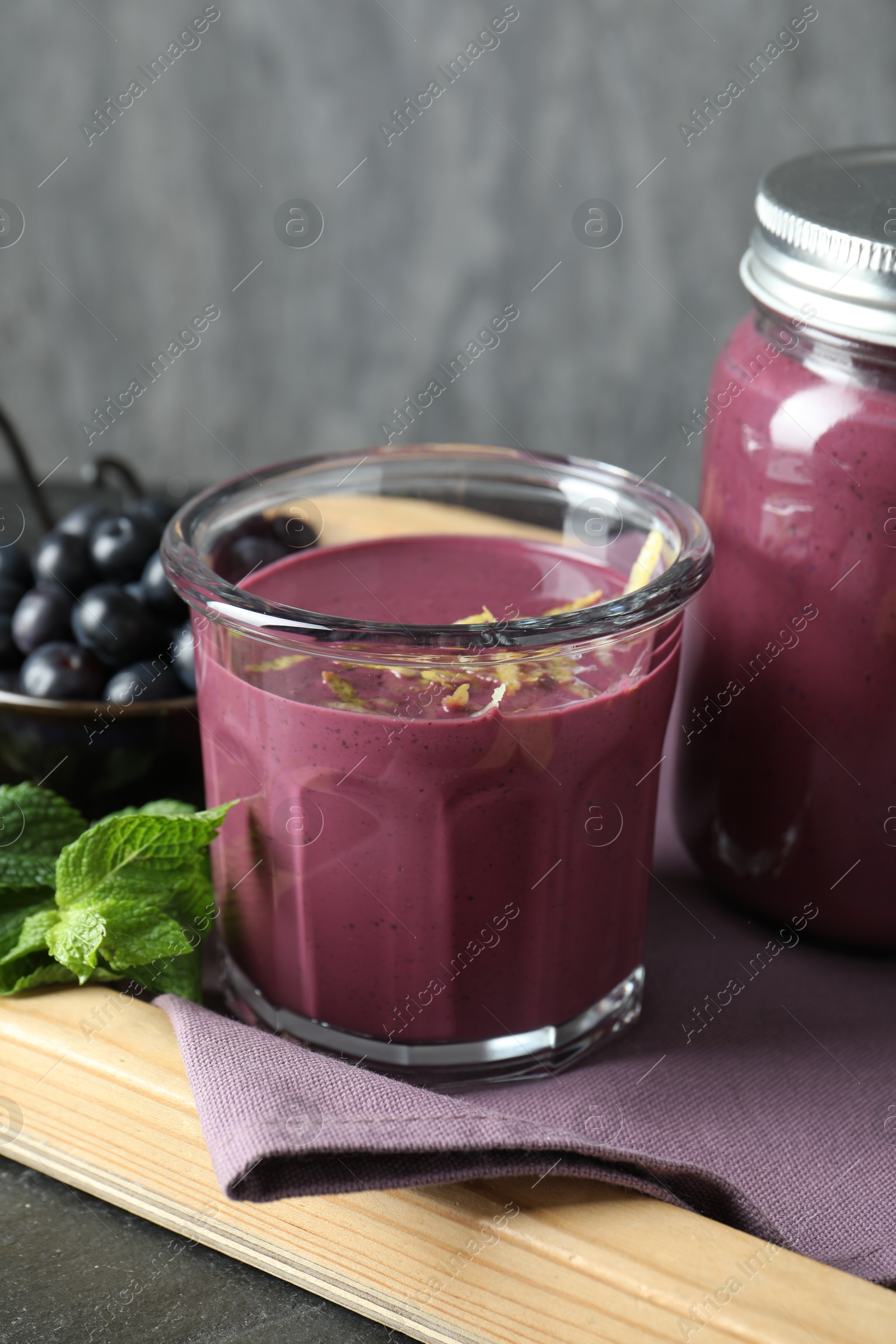 Photo of Tasty fresh acai juice with mint and berries on grey table