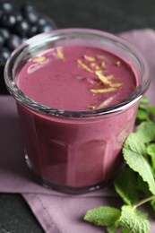 Tasty fresh acai juice with lemon zest in glass and mint on grey table, closeup