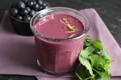 Photo of Tasty fresh acai juice with lemon zest in glass and mint on grey table, closeup