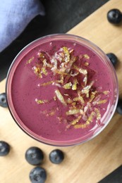 Photo of Tasty fresh acai juice with lemon zest in glass on grey table, top view