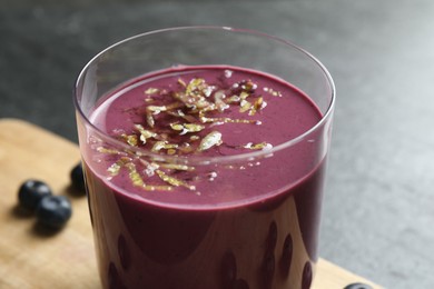 Photo of Tasty fresh acai juice with lemon zest in glass on grey table, closeup