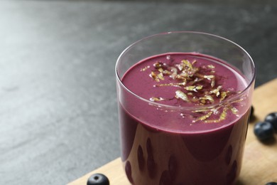 Photo of Tasty fresh acai juice with lemon zest in glass on grey table, closeup. Space for text