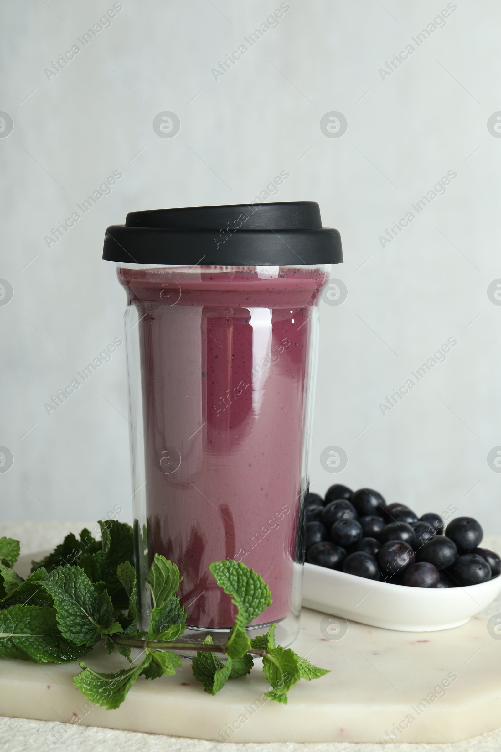 Photo of Tasty fresh acai juice in glass, mint and berries on light table