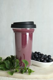 Tasty fresh acai juice in glass, mint and berries on light table