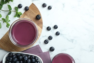 Photo of Tasty fresh acai juice in glasses, mint and berries on white marble table, flat lay. Space for text