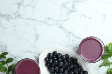 Photo of Tasty fresh acai juice in glasses, mint and berries on white marble table, flat lay. Space for text