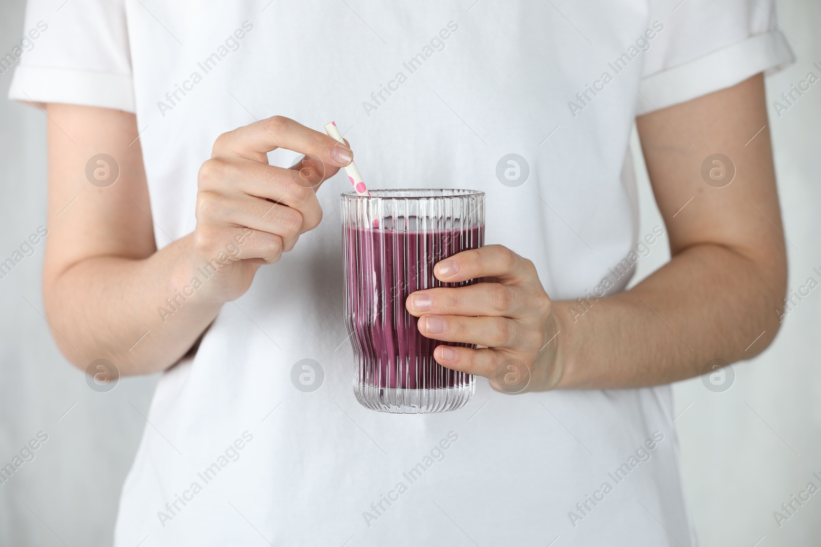 Photo of Woman with glass of tasty fresh acai juice on light grey background, closeup