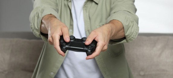 Photo of Smiling man playing video game with controller at home, closeup