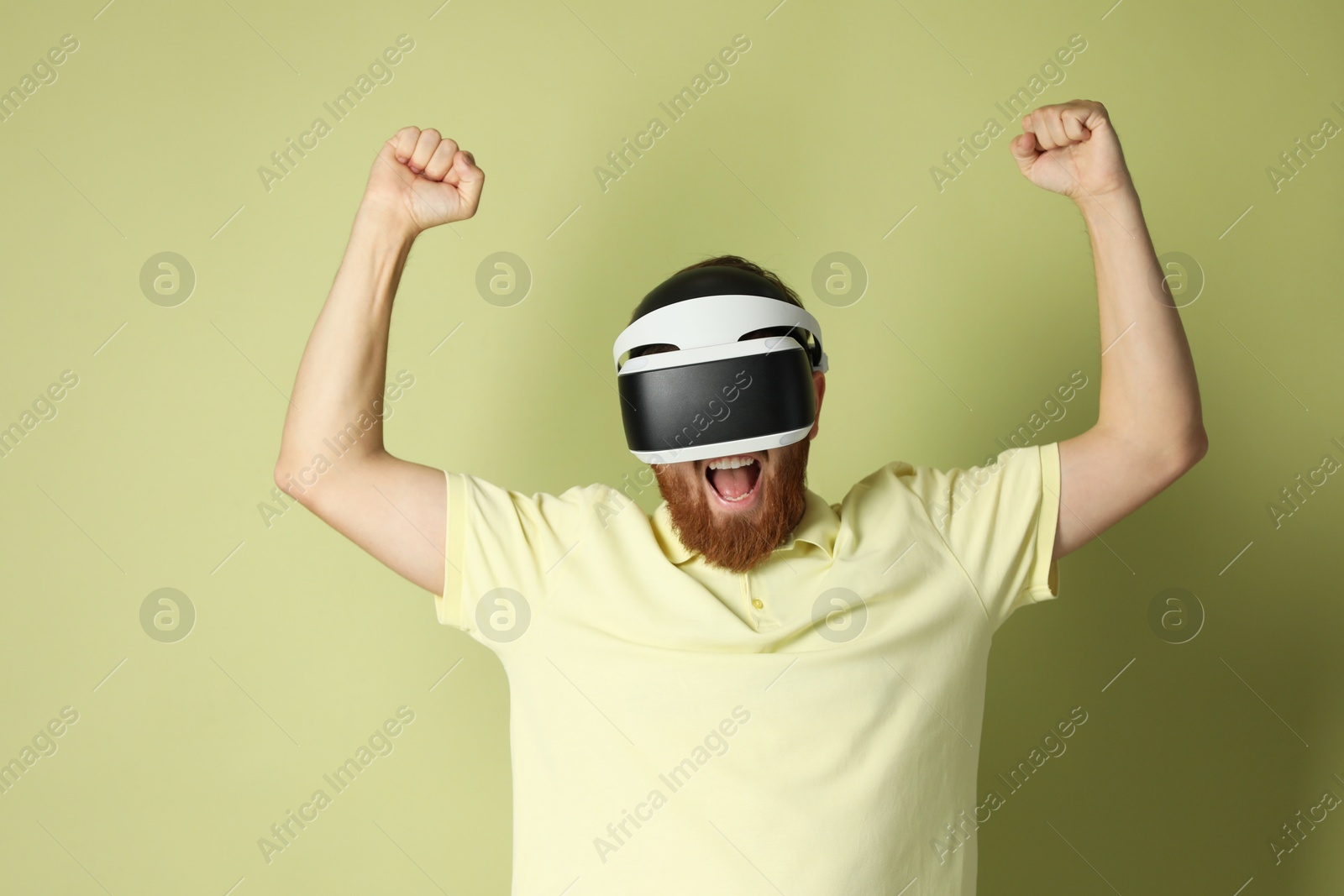 Photo of Emotional man using virtual reality headset on pale green background