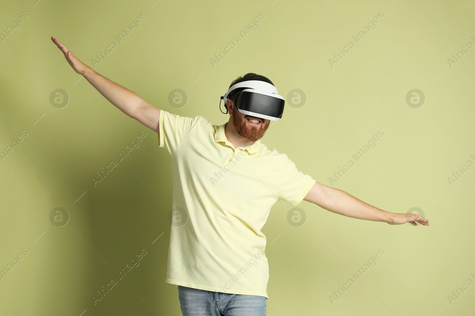 Photo of Smiling man using virtual reality headset on pale green background