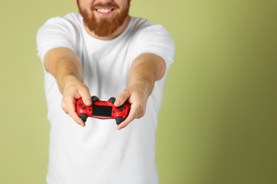 Photo of Man with game controller on pale green background, closeup. Space for text