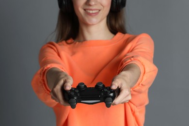 Photo of Happy woman playing video games with controller on gray background, closeup
