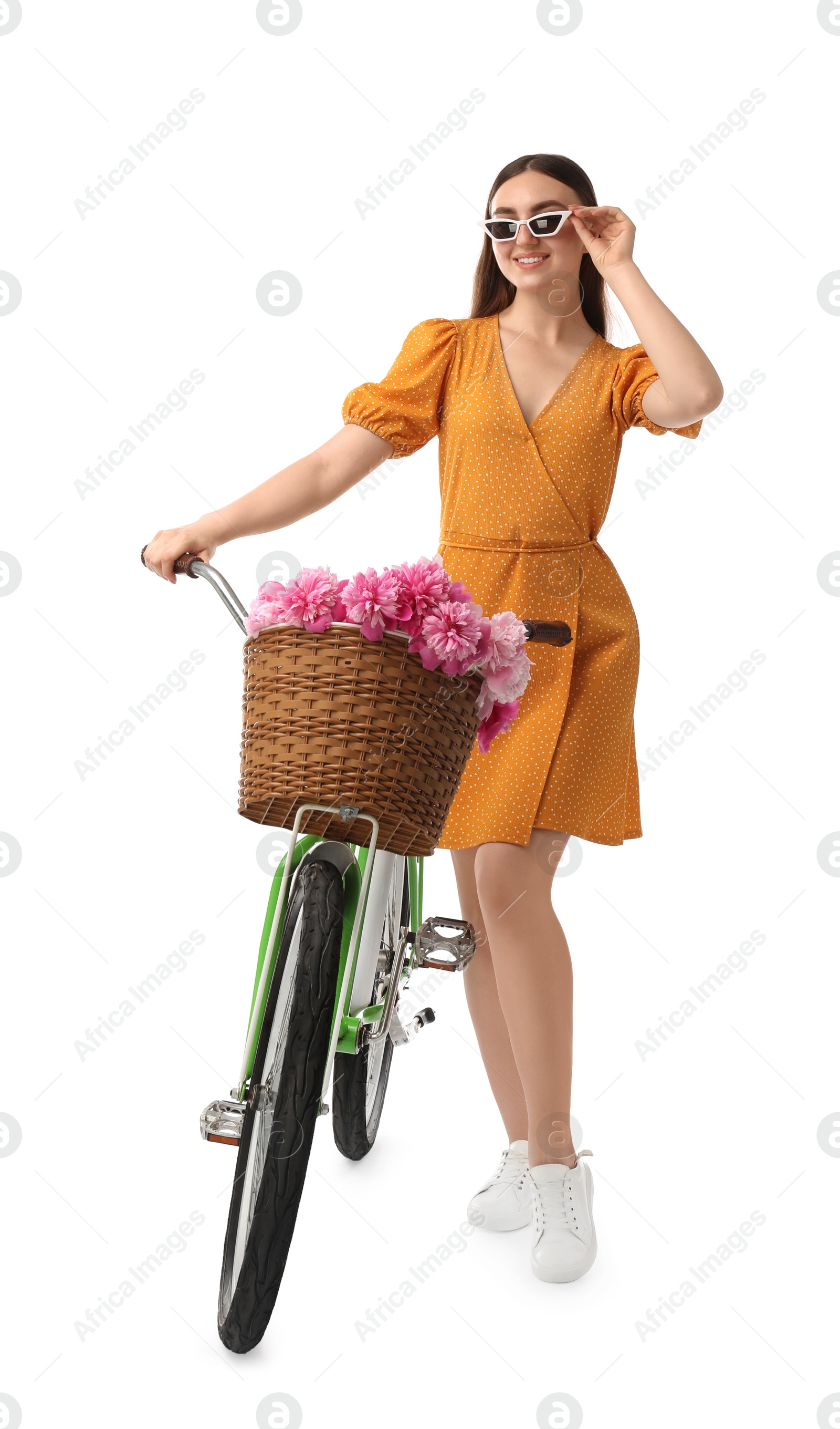 Photo of Woman in sunglasses with bicycle and basket of peony flowers isolated on white