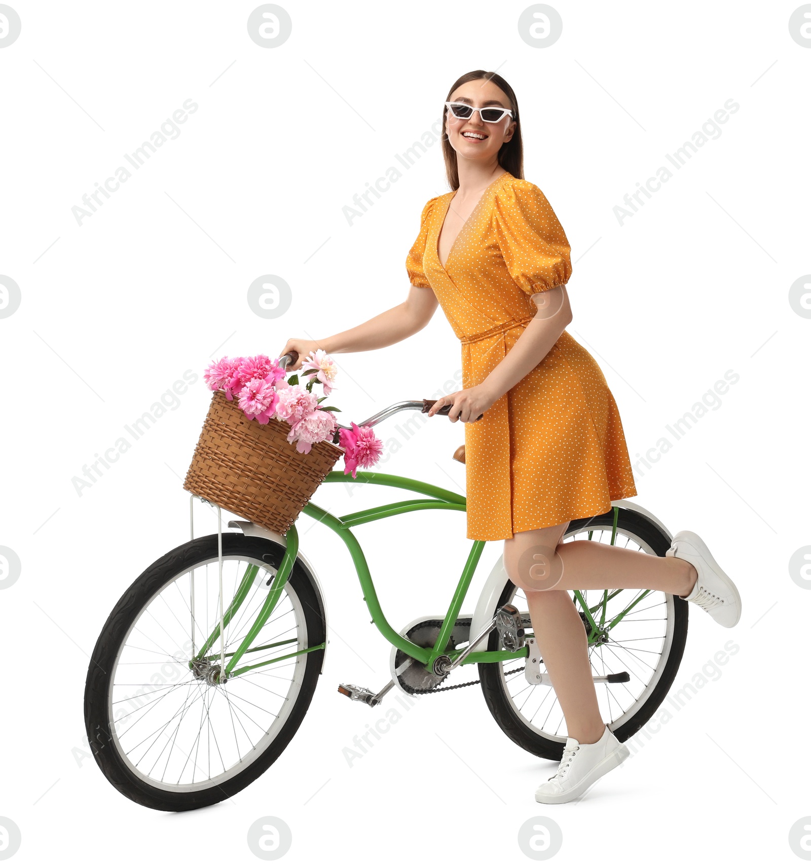 Photo of Smiling woman in sunglasses with bicycle and basket of peony flowers isolated on white