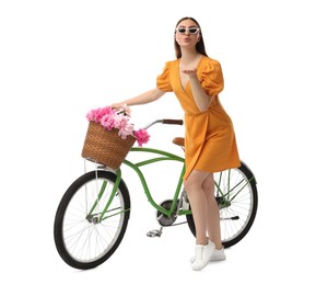 Photo of Woman in sunglasses with bicycle and basket of peony flowers blowing kiss isolated on white