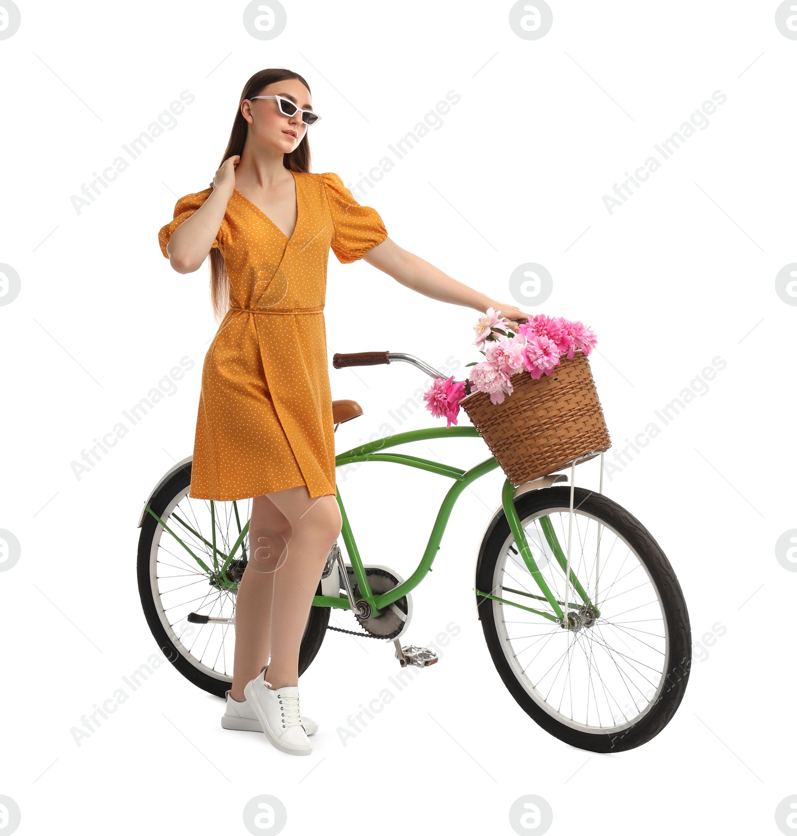 Photo of Woman in sunglasses with bicycle and basket of peony flowers isolated on white