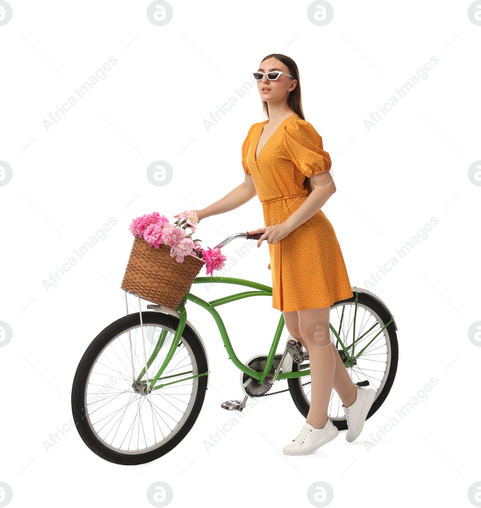 Photo of Woman in sunglasses with bicycle and basket of peony flowers isolated on white