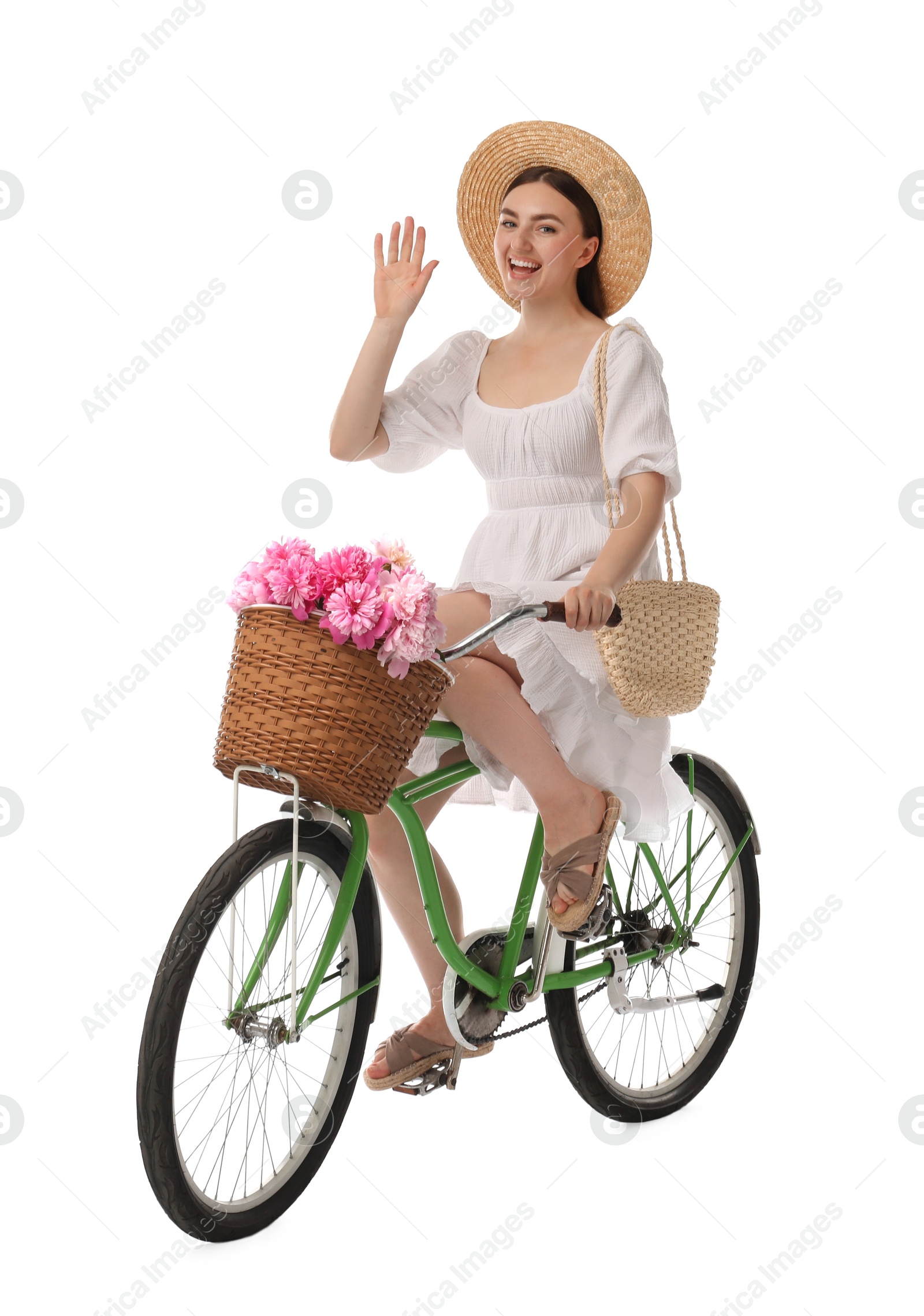 Photo of Happy woman riding bicycle with basket of peony flowers on white background