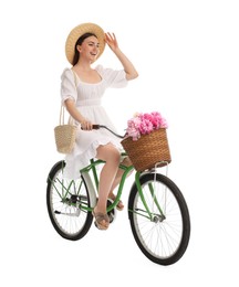 Photo of Happy woman riding bicycle with basket of peony flowers on white background