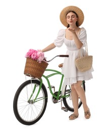Photo of Beautiful young woman with bicycle and basket of peony flowers blowing kiss on white background