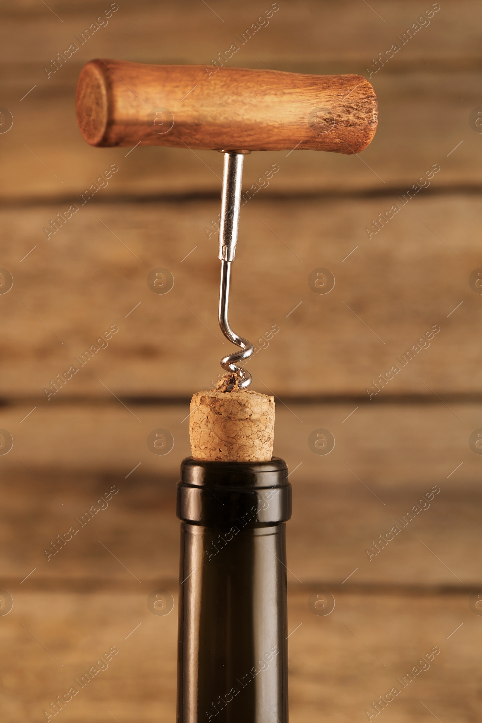 Photo of Wine bottle with corkscrew on wooden background, closeup