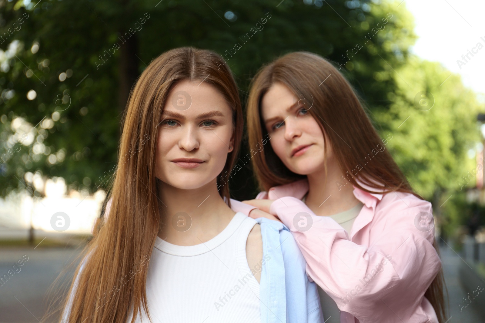 Photo of Portrait of two beautiful twin sisters outdoors