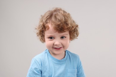 Portrait of cute little boy on grey background