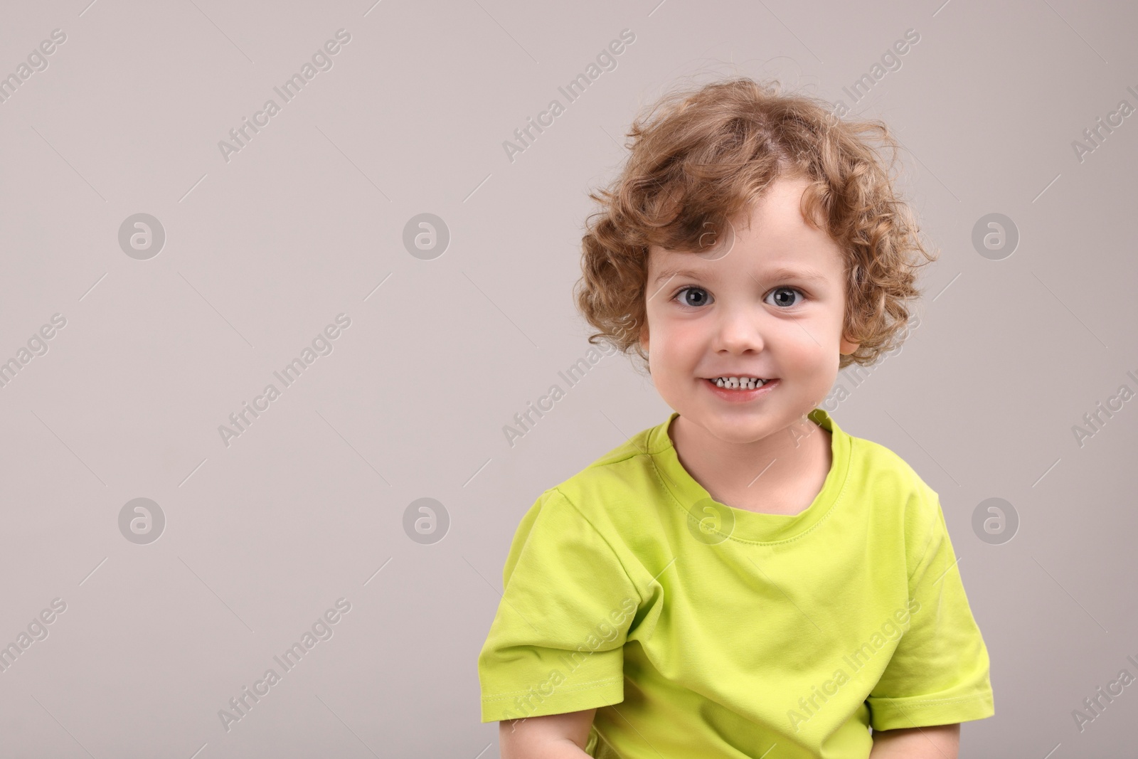 Photo of Portrait of cute little boy on grey background, space for text