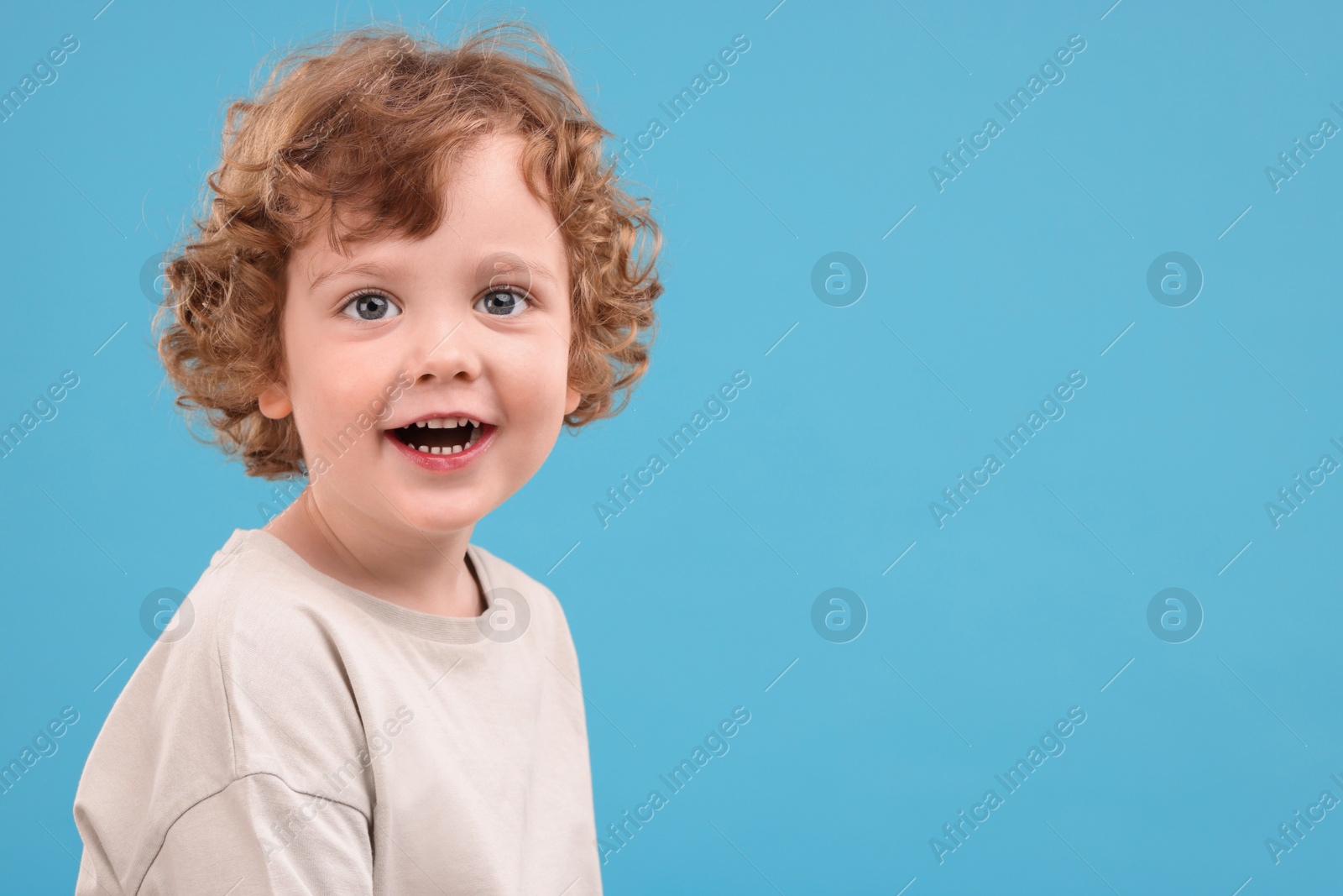 Photo of Portrait of cute little boy on light blue background, space for text