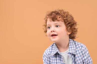 Portrait of cute little boy on beige background, space for text