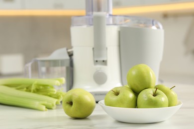 Modern juicer, celery and apples on white marble table in kitchen, selective focus