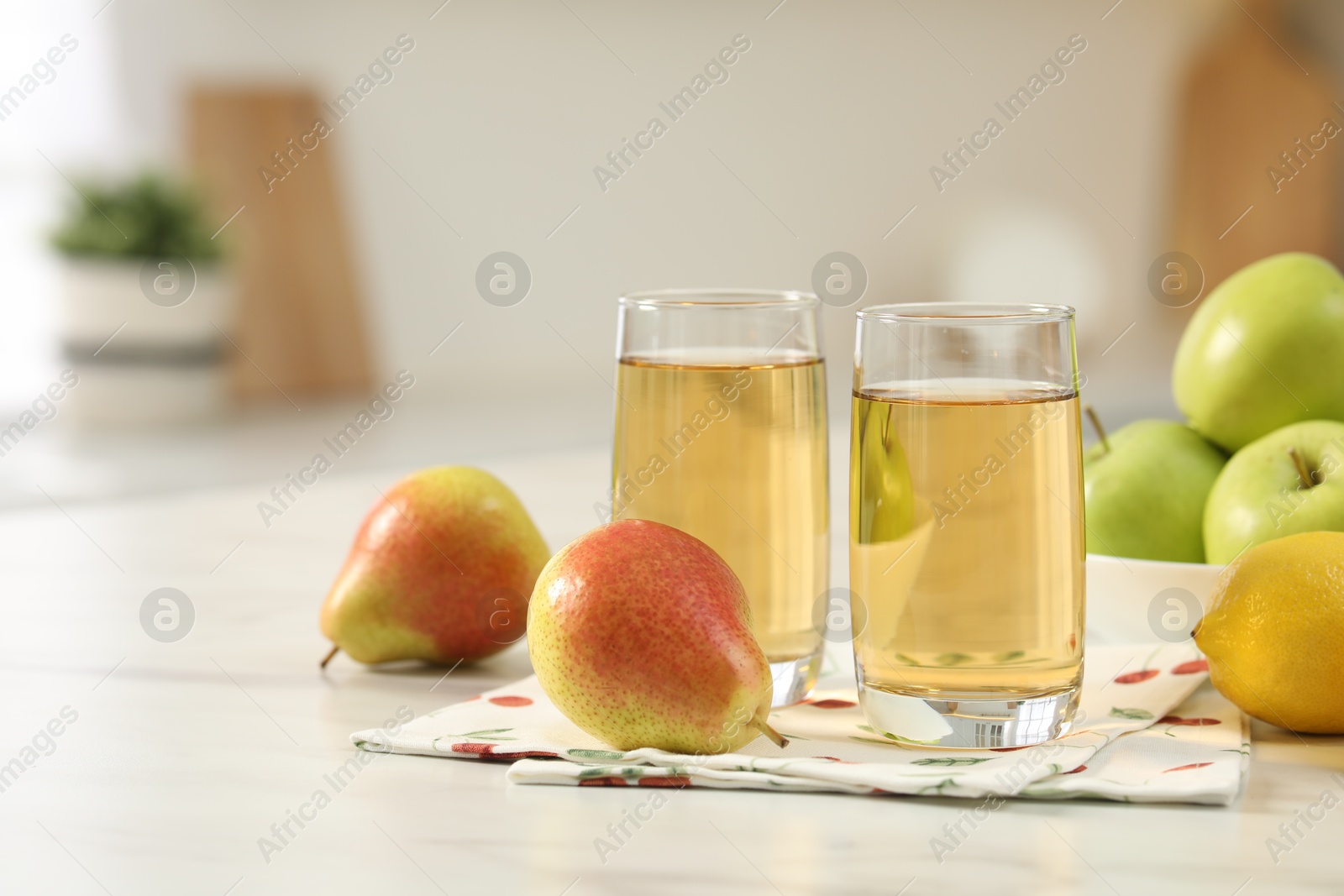 Photo of Glasses of fresh juice and fruits on white marble table in kitchen