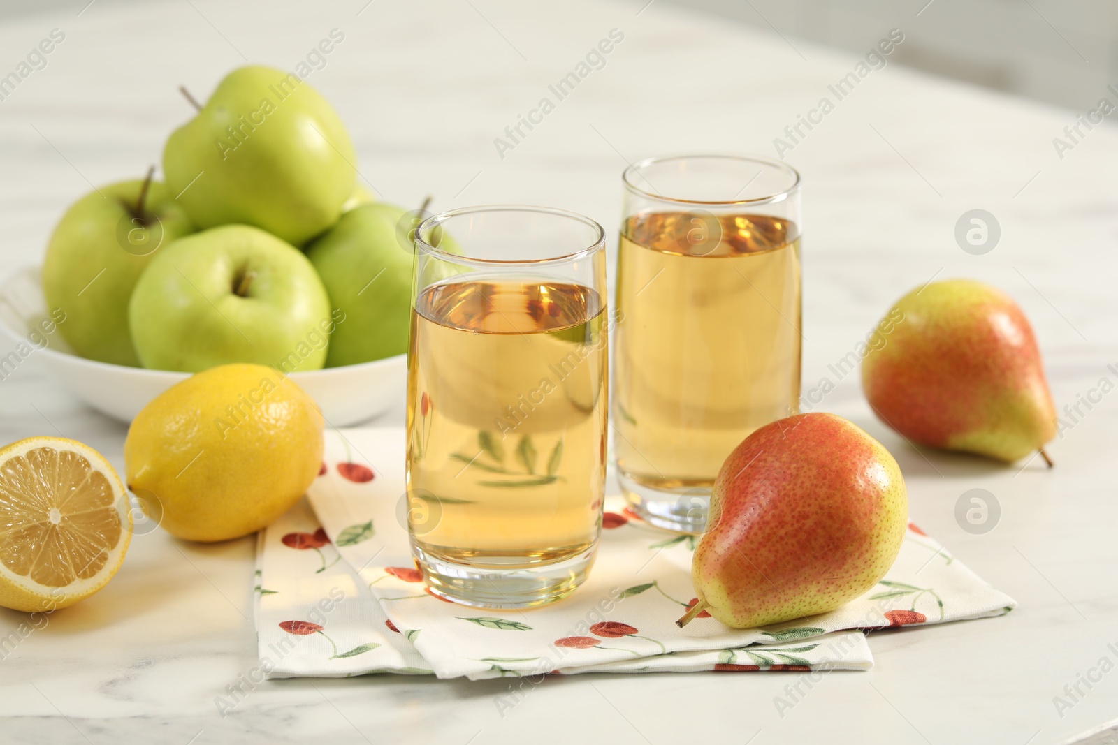 Photo of Glasses of fresh juice and fruits on white marble table in kitchen