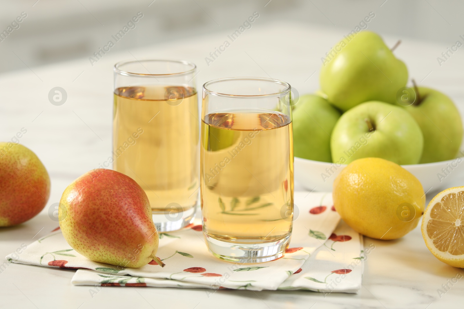 Photo of Glasses of fresh juice and fruits on white marble table in kitchen