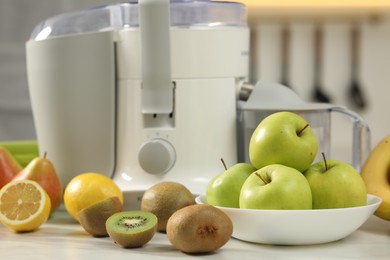 Photo of Modern juicer and fruits on white marble table in kitchen, selective focus