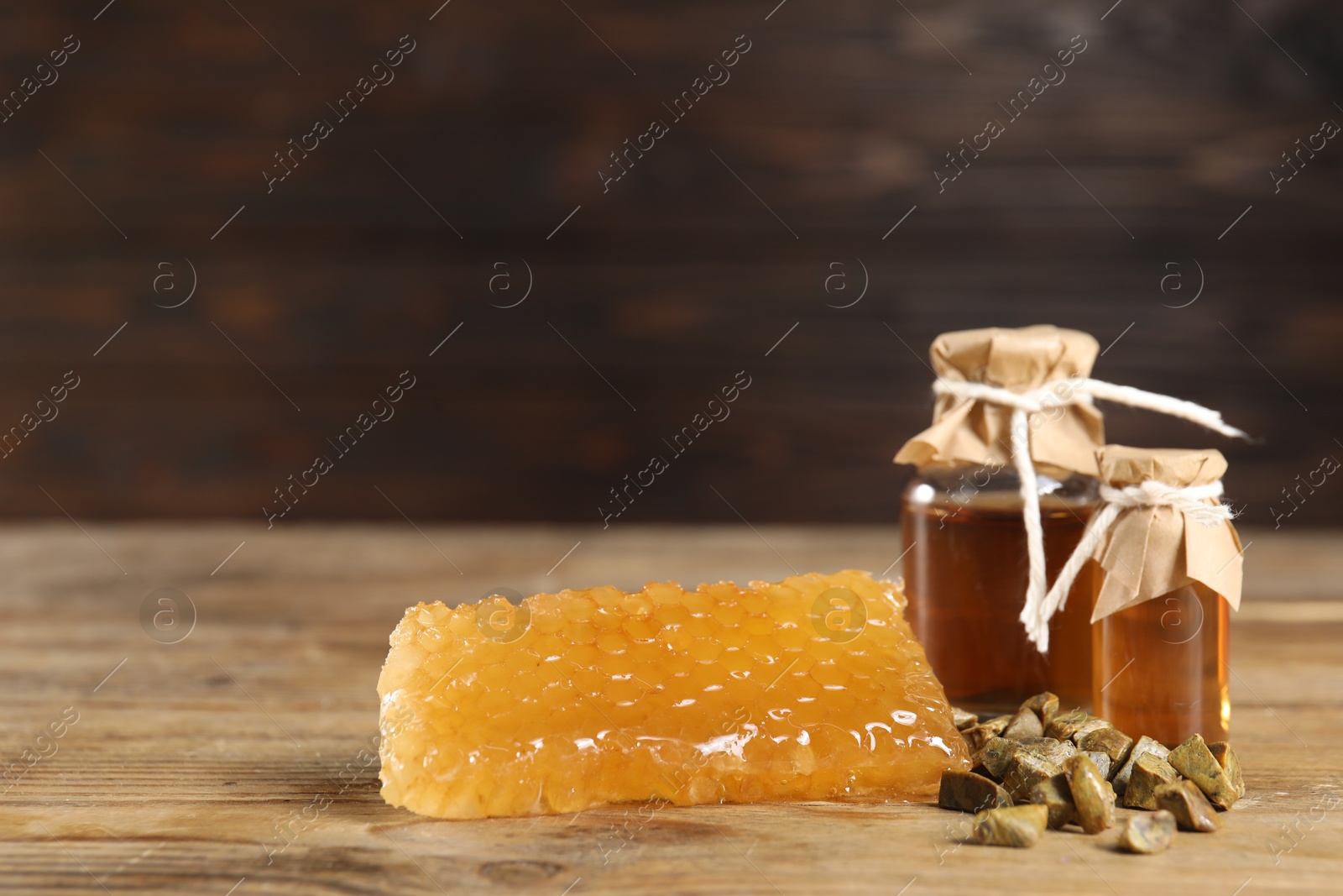 Photo of Natural honey tincture, propolis granules and sweet honeycomb on wooden table, space for text