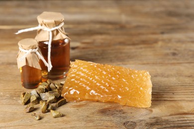 Photo of Natural honey tincture, propolis granules and sweet honeycomb on wooden table