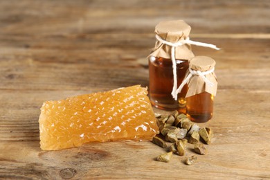 Photo of Natural honey tincture, propolis granules and sweet honeycomb on wooden table