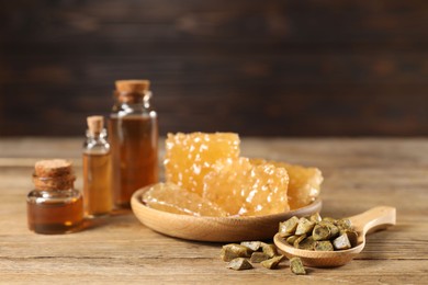 Photo of Natural honey tincture, propolis granules and sweet honeycombs on wooden table