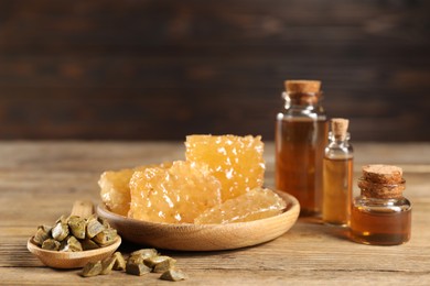 Photo of Natural honey tincture, propolis granules and sweet honeycombs on wooden table