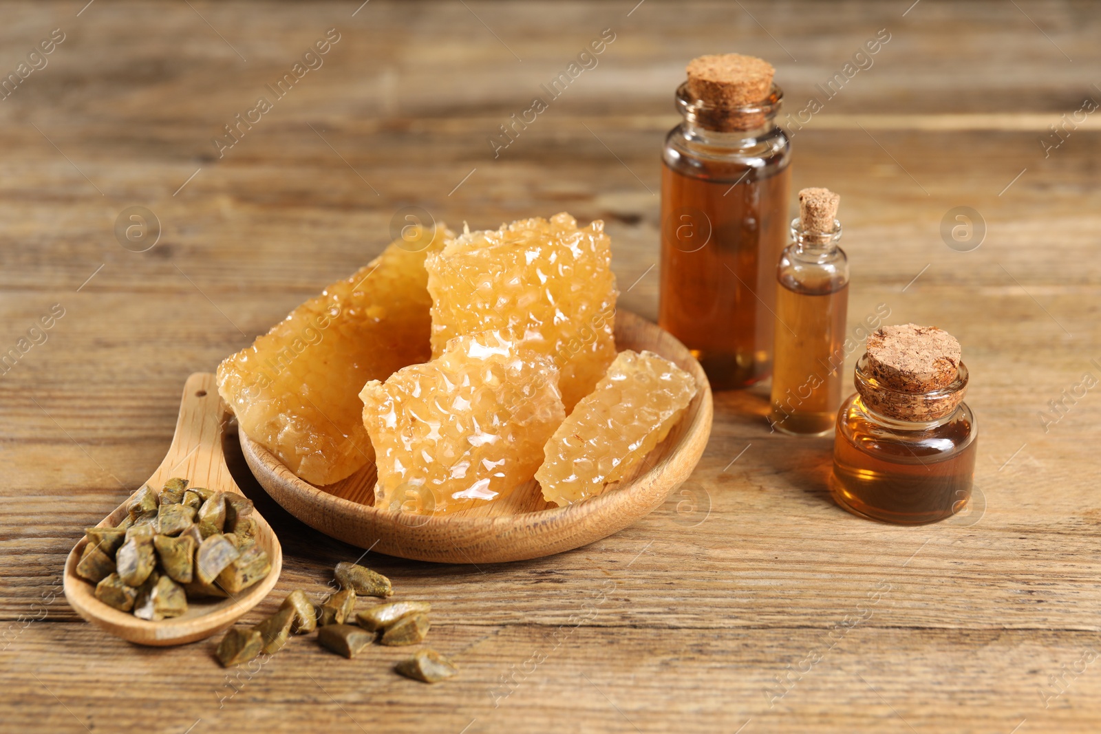 Photo of Natural honey tincture, propolis granules and sweet honeycombs on wooden table