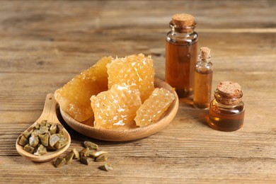 Photo of Natural honey tincture, propolis granules and sweet honeycombs on wooden table