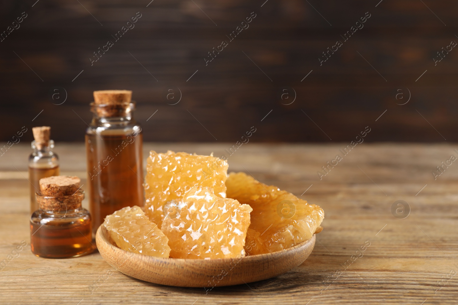 Photo of Natural honey tincture and sweet honeycombs on wooden table, closeup