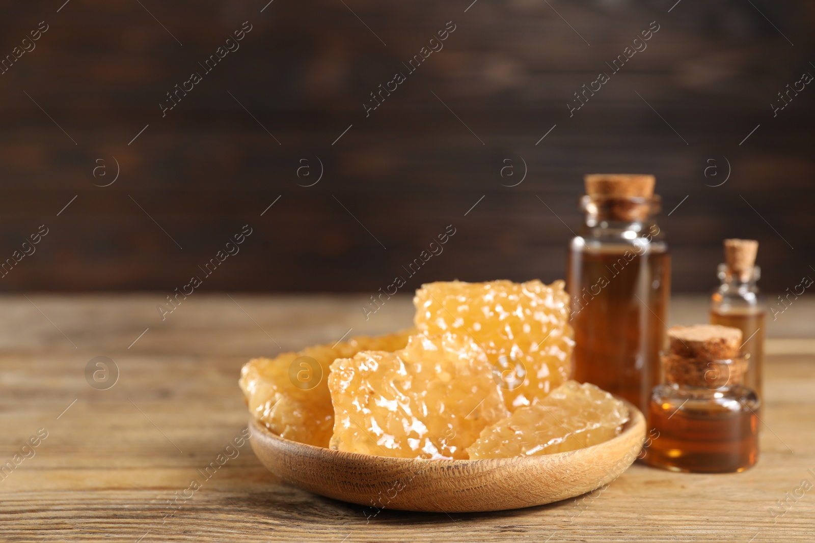 Photo of Natural honey tincture and sweet honeycombs on wooden table, closeup. Space for text