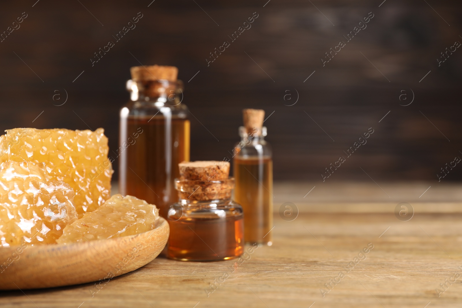 Photo of Natural honey tincture and sweet honeycombs on wooden table, closeup. Space for text