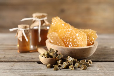 Photo of Natural honey tincture, propolis granules and sweet honeycombs on wooden table, closeup