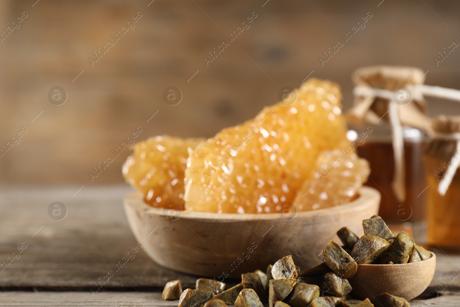 Photo of Natural honey tincture, propolis granules and sweet honeycombs on wooden table, closeup