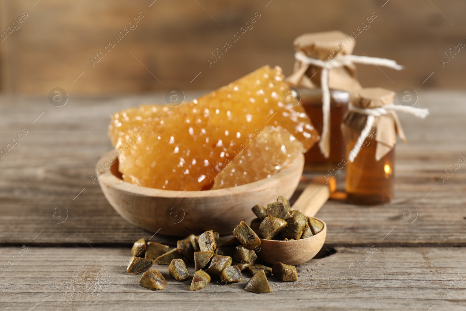 Photo of Natural honey tincture, propolis granules and sweet honeycombs on wooden table, closeup